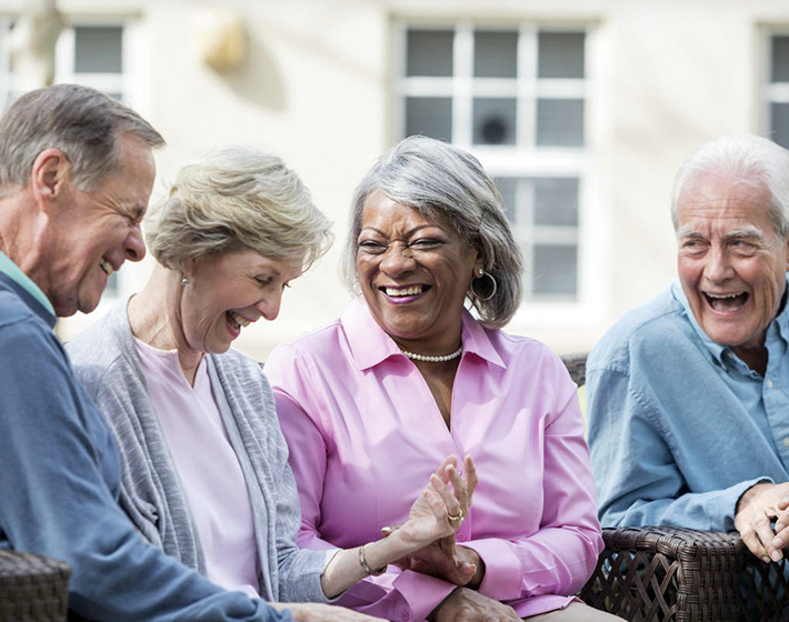 Multiracial senior friends sitting outdoors on patio talking