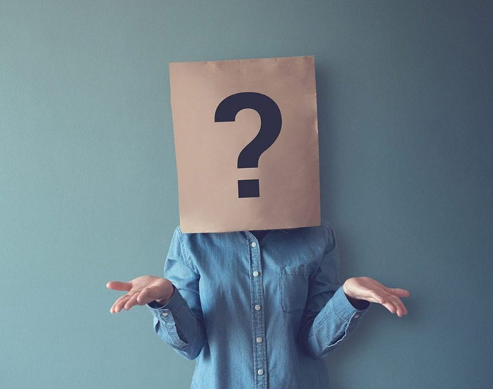 woman wears paperbag over her head with giant question mark