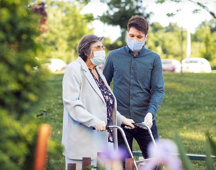 senior woman wearing a mask is helped by a young man wearing a mask