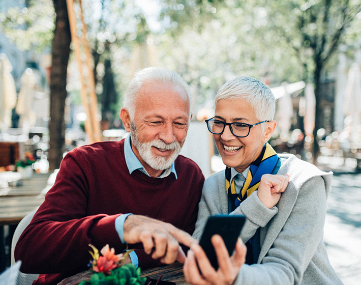 Mature couple using smartphone while seated at outdoor cafe