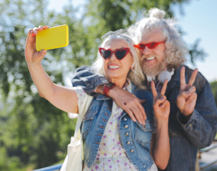 2 baby boomers smile as they take a selfie with a smartphone