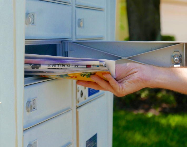 A person's hand is pulling direct mail out of their mailbox.