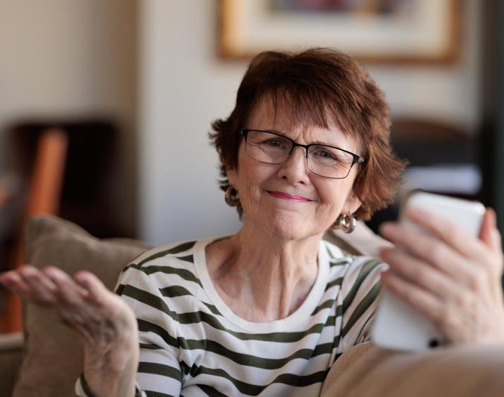 Senior woman holding her phone, frustrated with ageism.