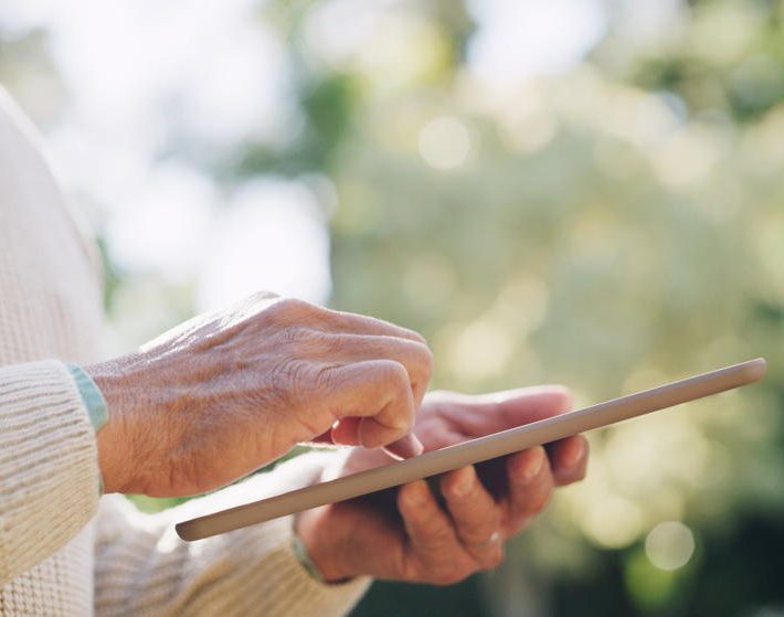 senior man taps a tablet sending signals of intent to Market Signal Intelligence collectors